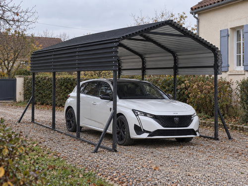 Carport acier thermolaqué noir 4,5 x 3 m installé sur une allée gravillonnée, voiture citadine abritée