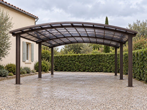 Carport aluminium abritant un camping-car blanc dans une allée en gravier